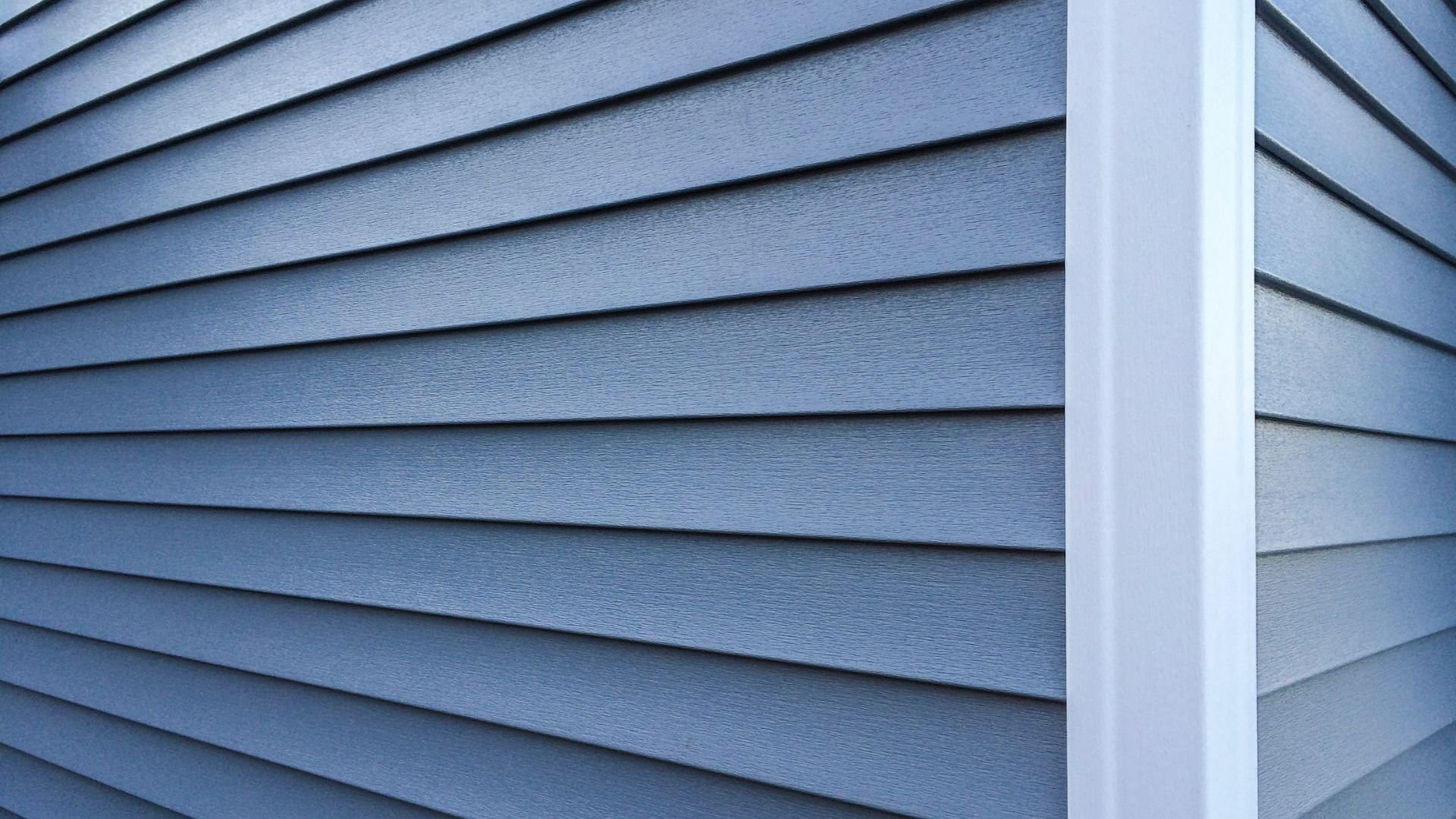 Blue-gray horizontal siding on a house exterior with white corner trim